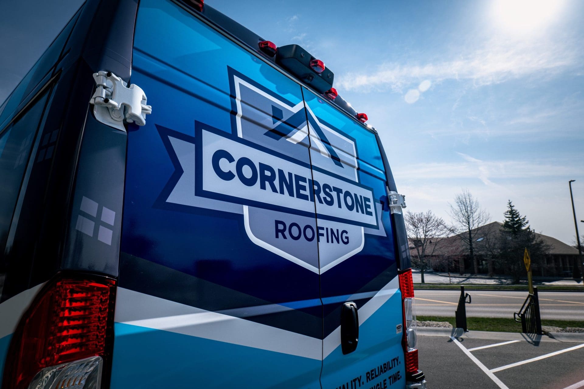 Back of a commercial van with a business fleet vehicle wrap promoting a roofing business